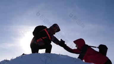 男人们互相帮助，在日落时分互相牵手，互相伸展，征服一座高山的山顶。游客的团队合作和胜利。旅行时的自然条件寒冷.